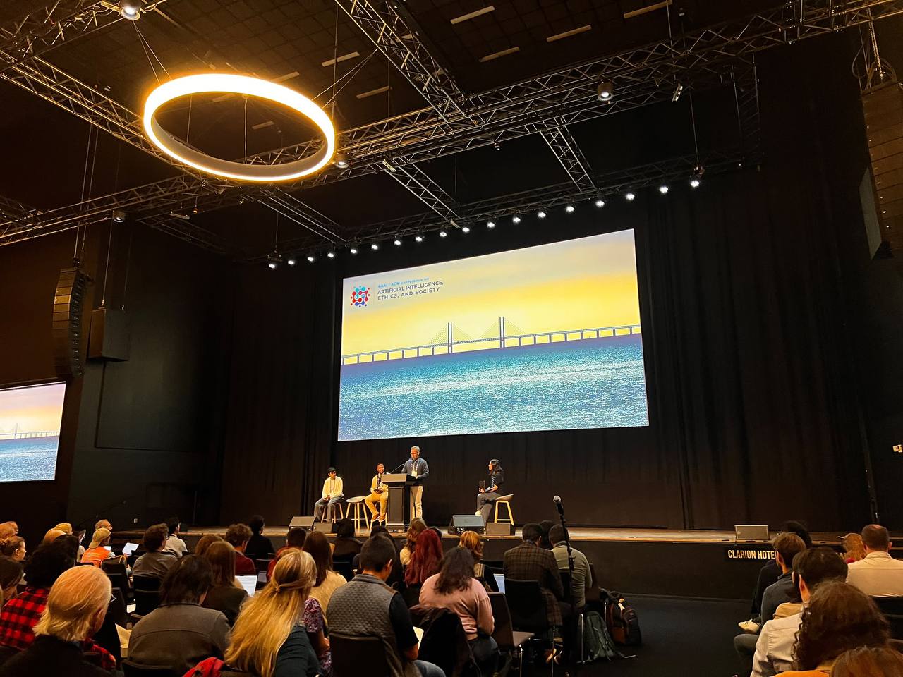 AIES 2026 Discussion Session 1 at Malmo Live: panel on stage under the conference screen, audience in the foreground.