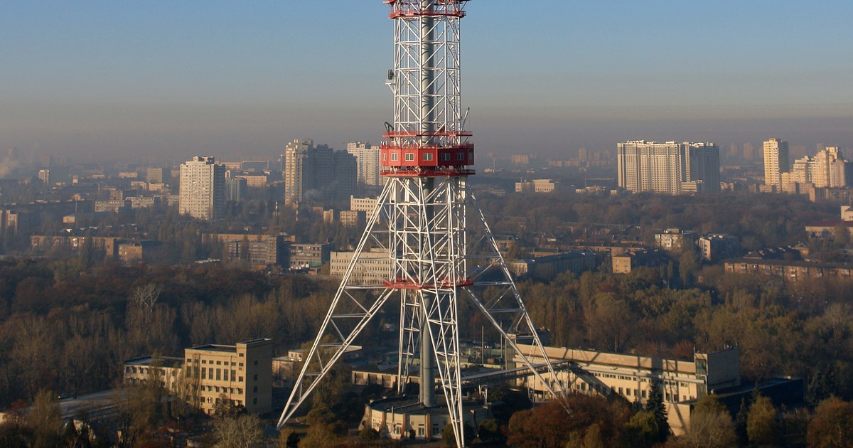 The red and white lattice structure of the Kyiv TV Tower rising above the city of Kyiv